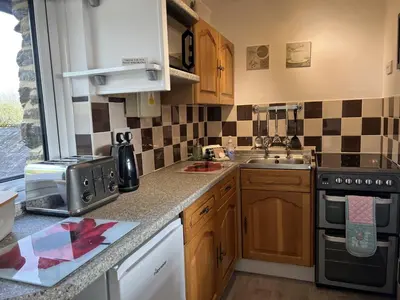a kitchen with a sink and a stove top oven at Hop Loft-Barn Conversion, with access to Pool & Hot Tub-at Fox Valley Cottages in Looe