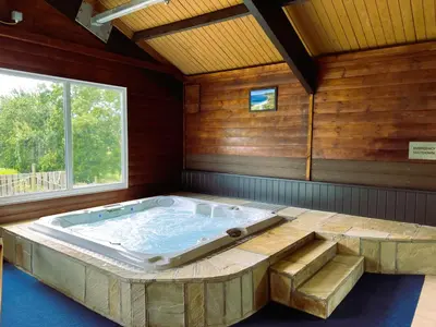 a jacuzzi tub in a room with a window at Hop Loft-Barn Conversion, with access to Pool & Hot Tub-at Fox Valley Cottages in Looe