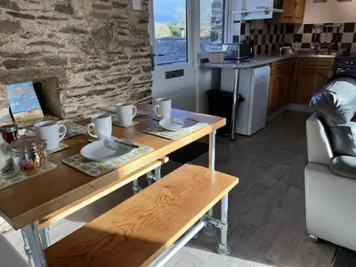 a kitchen with a wooden table with dishes on it at Hop Loft-Barn Conversion, with access to Pool & Hot Tub-at Fox Valley Cottages in Looe