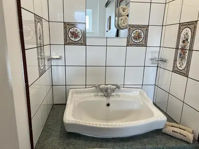 a white sink in a tiled bathroom at Hop Loft-Barn Conversion, with access to Pool & Hot Tub-at Fox Valley Cottages in Looe