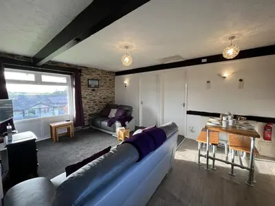 a living room with a couch and a table at Hop Loft-Barn Conversion, with access to Pool & Hot Tub-at Fox Valley Cottages in Looe