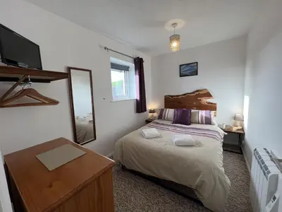 a bedroom with a bed and a mirror and a dresser at Hop Loft-Barn Conversion, with access to Pool & Hot Tub-at Fox Valley Cottages in Looe