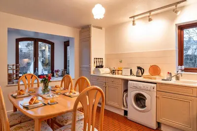 a kitchen with a table and a sink and a dishwasher at Finest Retreats - Tregenna Court in Falmouth