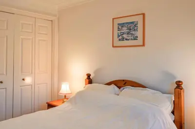 a bed with white sheets and a picture on the wall at Finest Retreats - Tregenna Court in Falmouth