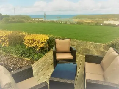 a patio with a bench and a chair and a table at Cottage in Crantock, seaviews, 10min walk to beach in Crantock
