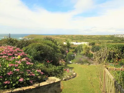 a garden with flowers and the ocean in the background at Cottage in Crantock, seaviews, 10min walk to beach in Crantock
