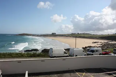 a group of vehicles parked on a road near a beach at Fistral View Apartment in Newquay