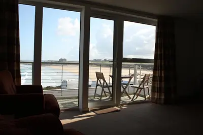 a room with a balcony with a table and chairs at Fistral View Apartment in Newquay