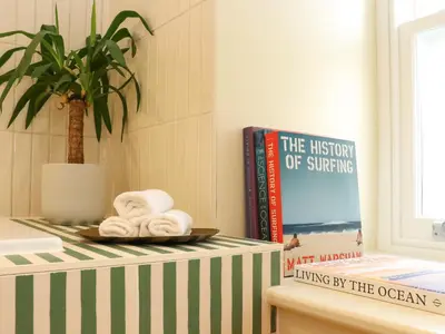a bathroom with a shelf with books and towels at Mavericks Wave in St. Agnes