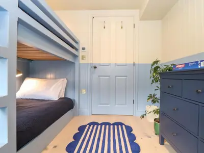 a small bedroom with a bed and a blue door at Mavericks Wave in St. Agnes