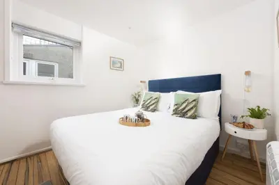 a bedroom with a large white bed with a window at 3 Pentowan Court, Carbis Bay in Carbis Bay