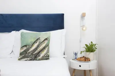 a bed with a painting of fish on a pillow at 3 Pentowan Court, Carbis Bay in Carbis Bay