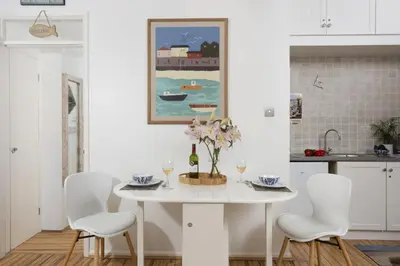 a white kitchen with a white table and chairs at 3 Pentowan Court, Carbis Bay in Carbis Bay