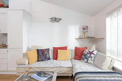 a living room with a white couch with colorful pillows at 3 Pentowan Court, Carbis Bay in Carbis Bay