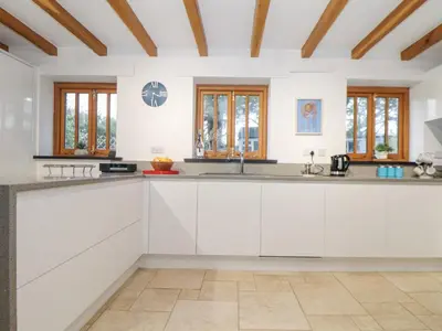 a kitchen with white cabinets and wooden ceilings at Splatt Barn in Wadebridge