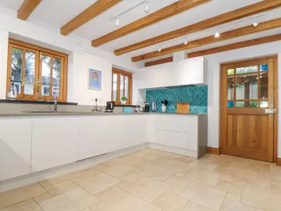 a kitchen with white cabinets and a wooden door at Splatt Barn in Wadebridge