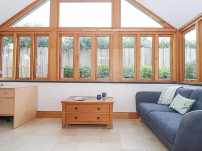 a living room with a blue couch and windows at Splatt Barn in Wadebridge