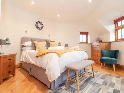 a bedroom with a large bed and a blue chair at Splatt Barn in Wadebridge