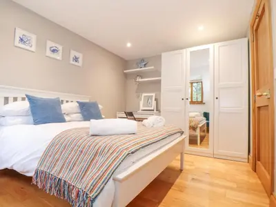 a bedroom with a bed with blue pillows and a table at Splatt Barn in Wadebridge