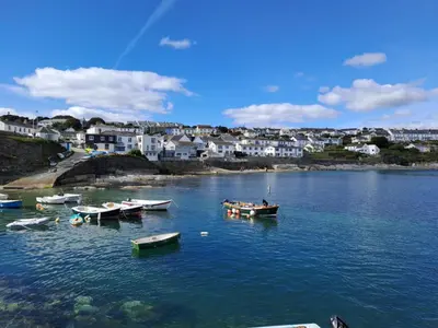 a group of boats in a body of water with houses at Pengerein in Porthscatho