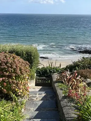 a path leading to a beach with a bench at Pengerein in Porthscatho