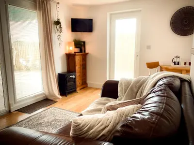 a living room with a leather couch and a window at The Studio in Bude