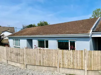 a white house behind a wooden fence at Trelawne in Bude