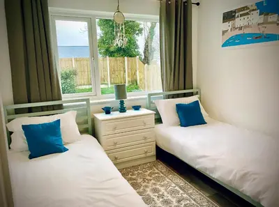 two twin beds in a room with a window at Trelawne in Bude