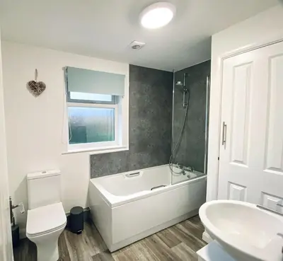 a bathroom with a tub and a toilet and a sink at Trelawne in Bude