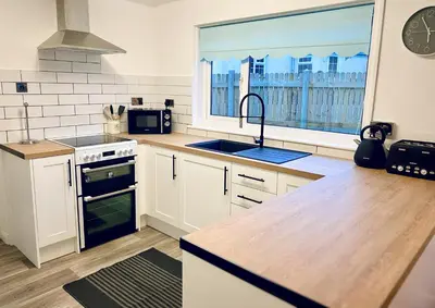 a kitchen with a sink and a large window at Trelawne in Bude