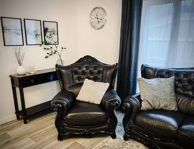 a living room with two leather chairs and a clock at Trelawne in Bude