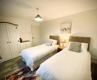 a bedroom with two beds and a dresser at Trelawne in Bude