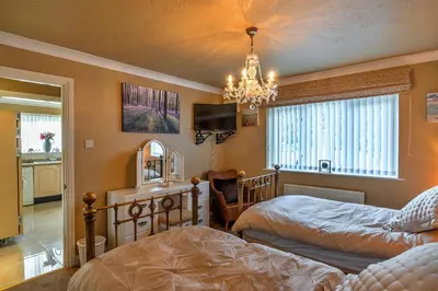 a bedroom with two beds and a chandelier at Finest Retreats - Harvest Moon in Newquay