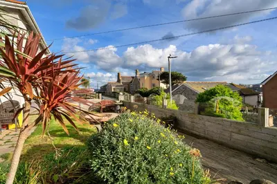 a garden with a retaining wall and some houses at Finest Retreats - Harvest Moon in Newquay