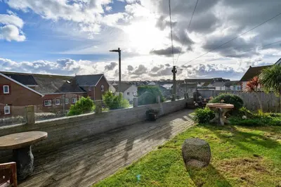 a backyard with a wooden deck with a table and bench at Finest Retreats - Harvest Moon in Newquay