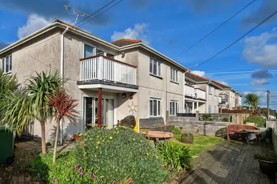 a house with a balcony and a table in a yard at Finest Retreats - Harvest Moon in Newquay