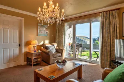 a living room with a chandelier and a chair and a table at Finest Retreats - Harvest Moon in Newquay