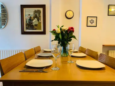 a wooden table with plates and glasses and flowers on it at Maypole Cottages No 10 Broad Street Padstow in Padstow