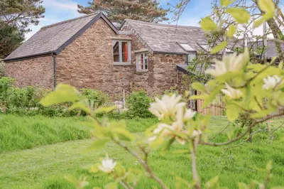 a stone house with a red window in a yard at 2 Bed in St. Mawgan oc-l30651 in Saint Mawgan