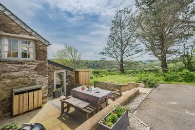 a stone house with a table and chairs on a patio at 2 Bed in St. Mawgan oc-l30651 in Saint Mawgan