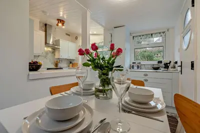 a white kitchen with a table with flowers in a vase at 2 Bed in Mawgan oc-c30671 in Mawgan
