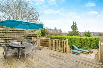 a wooden deck with a table and an umbrella at 2 Bed in Mawgan oc-c30671 in Mawgan