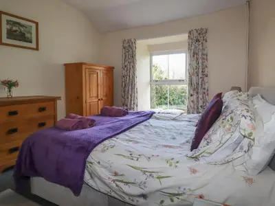 a bedroom with a large bed and a window at Bramble Cottage in Hayle