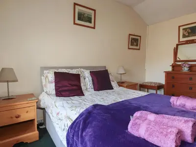 a bedroom with a bed with purple sheets and pillows at Bramble Cottage in Hayle