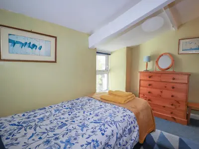 a bedroom with a bed and a dresser and a window at Bramble Cottage in Hayle