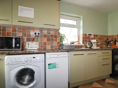 a kitchen with a washing machine and a microwave at Bramble Cottage in Hayle