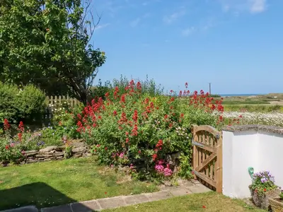 a garden with flowers and a wooden gate at Bramble Cottage in Hayle