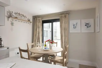 a table and chairs in a kitchen with a window at Harlyn Folly, Apartment 6, Harlyn in St Merryn