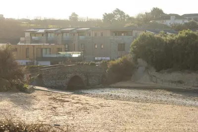 a stone bridge over a river with buildings in the background at Harlyn Folly, Apartment 6, Harlyn in St Merryn