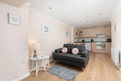 a living room with a chair and a kitchen at 7 Lower Talland Apartments in St Ives